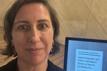 Tłumaczka przy plakacie konferencji naukowej "Języki żydowskie i polityka"